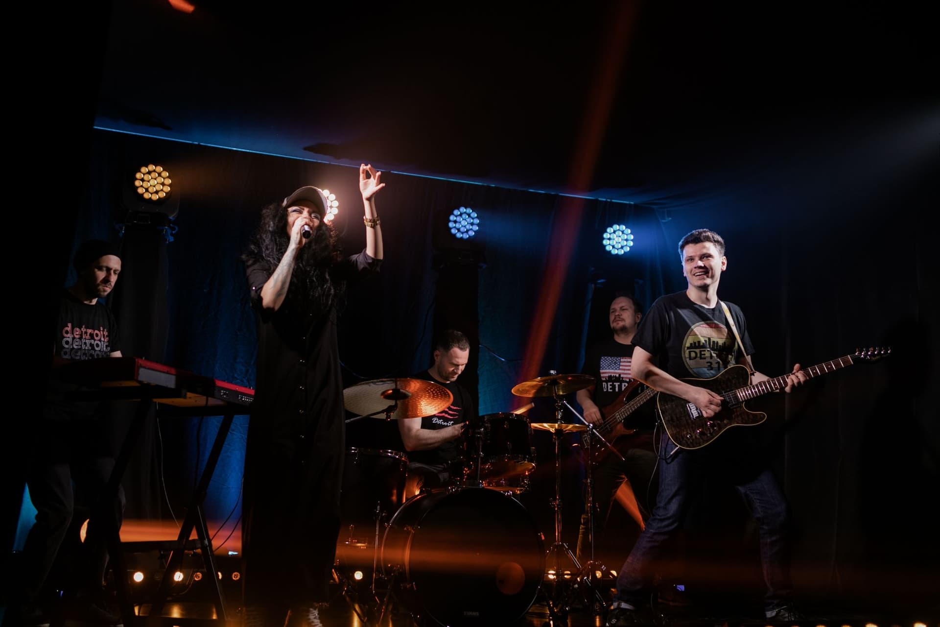 Liveband på en scene med gult scenelys og publikum foran