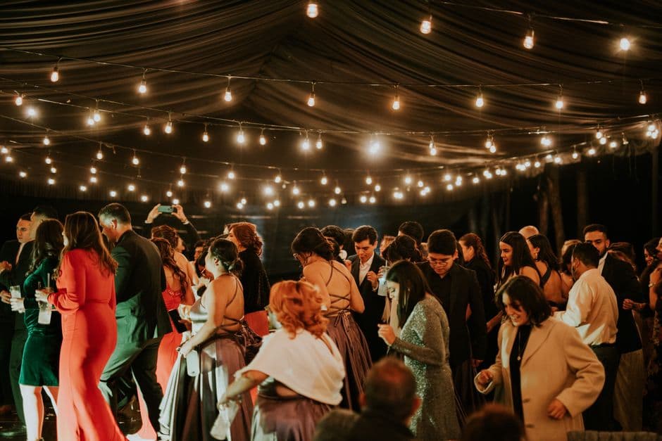 Festgjester danser under lyslenker i et telt om kvelden